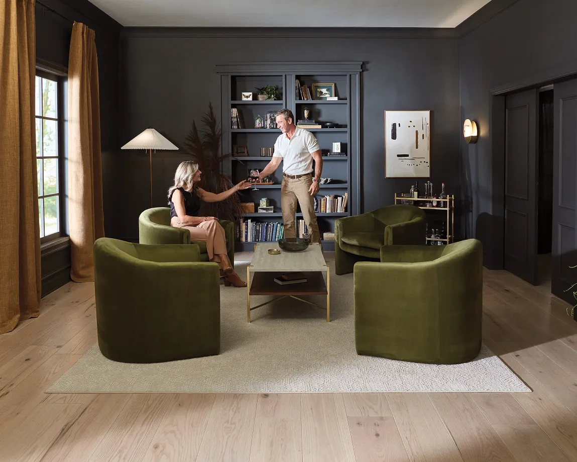 Cozy living room with light hardwood flooring, green armchairs, and a beige rug